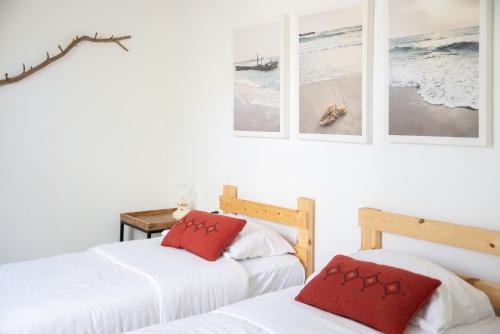 two beds in a white room with pictures on the wall at חאן טשרניחובסקי in ‘Ofer