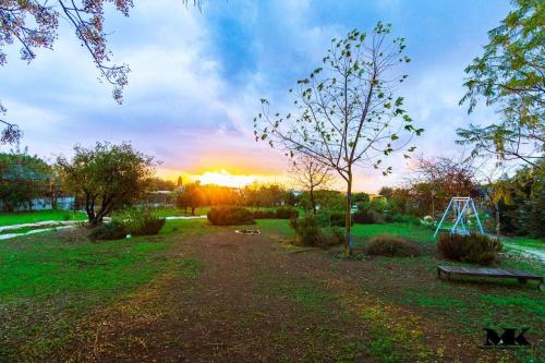 a park with a bench and the sunset in the background at חאן טשרניחובסקי in ‘Ofer