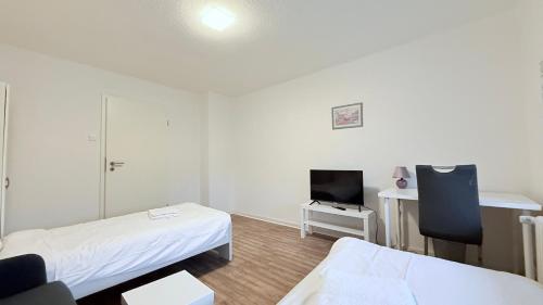 a small room with two beds and a tv at Neumünster Apartments direkt an der Stadthalle mit WLAN & Parkplatz in Neumünster