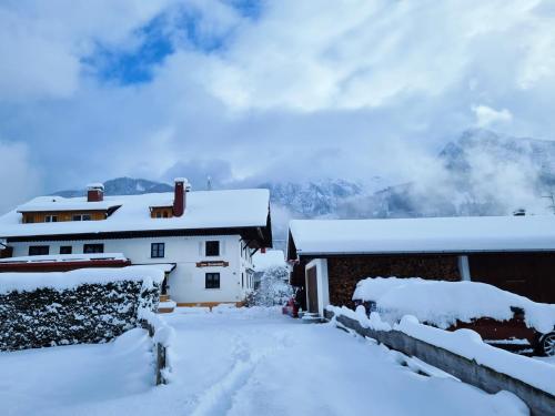 a house covered in snow with mountains in the background at Schittlerhof in Fischen