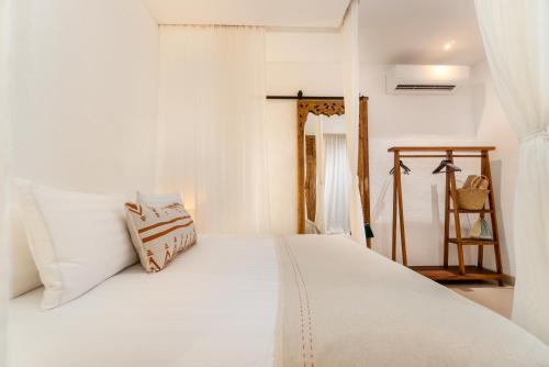 a bedroom with a white bed with white sheets at The Balangan Hotel in Jimbaran