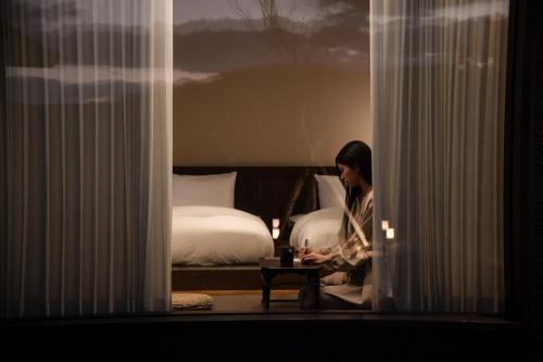 a woman sitting in a room with a bed at Generous Jeju in Jeju