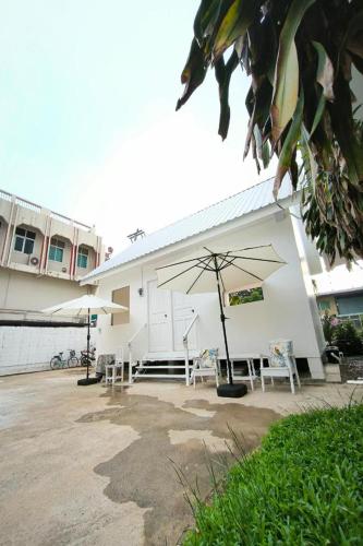 a white building with tables and umbrellas in front of it at Ban Ye in Phayao