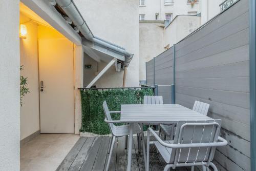 une table blanche et des chaises sur un balcon dans l'établissement An Enchanting Parisian hideaway, à Paris