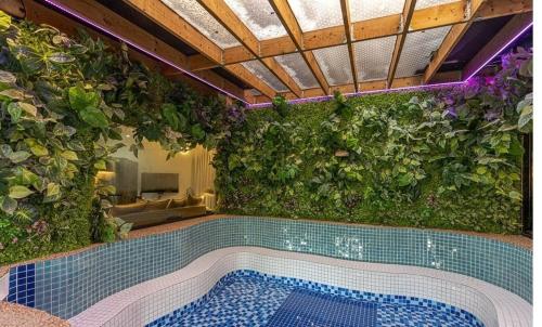 an indoor swimming pool with a green wall with plants at By Hanlim in Jeju