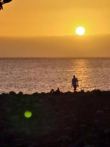 a person walking on the beach at sunset at Apartment Palma Madeira wandern und tauchen in Caniço