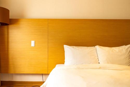 a bed with a wooden headboard and white pillows at Leesangwon Museum of Art - Museumstay in Tŏkkol-mal