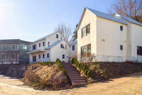 a white house with a stairway leading up to it at Doomildoomil Poolvilla in Gapyeong