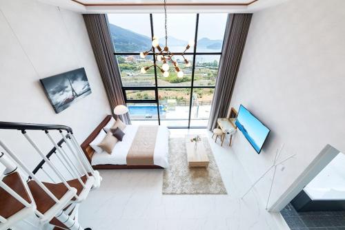 a bedroom with a bed and a large window at Geoje Harakeke Pension in Geoje 