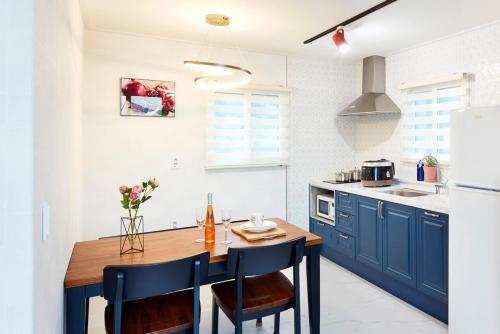 a kitchen with a wooden table and blue cabinets at Geoje Harakeke Pension in Geoje 
