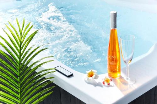 a bottle of alcohol and glasses on a table next to a swimming pool at Geoje Harakeke Pension in Geoje 