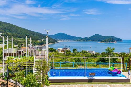 a swimming pool with a view of the water at Geoje Harakeke Pension in Geoje 