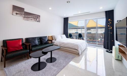 een slaapkamer met een bed, een bank en een tafel bij Geoje Star Marine Pool Villa in Geoje 