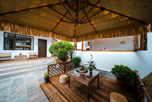 a patio with a wooden table and a large roof at The Whisperer Guanshan Private Residence Hotel in Dali