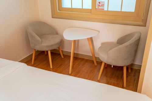 two chairs and a table and a bed in a room at Jeju Amor House Oceanview Oreum in Jeju