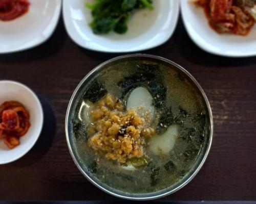 a bowl of food on a table with plates of food at Jeju Amor House Oceanview Oreum in Jeju