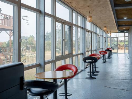 a row of tables and chairs in a room with windows at Jeju Amor House Oceanview Oreum in Jeju