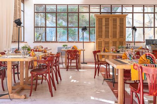 a restaurant with wooden tables and chairs and windows at Le Grand Hôtel in Molitg les Bains