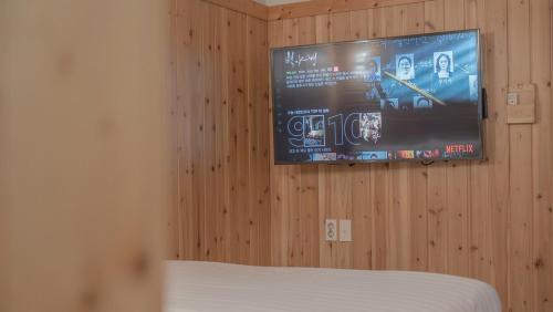 a bedroom with a tv on a wooden wall at Gyeongju Finrandia Pension in Gyeongju