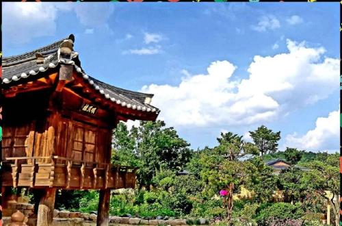 un piccolo edificio in legno con un tetto di fronte agli alberi di Manhoe Gotaek a Bonghwa