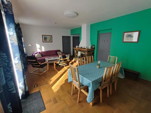 - un salon avec une table, des chaises et un mur vert dans l'établissement Au pont de Tuarelli, Ludique, Galeria, Corse, à Manso