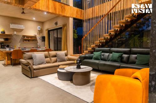 a living room with two couches and a table at StayVista at Urban Escape - 2 Pools, Lawn & WiFi in Jaipur