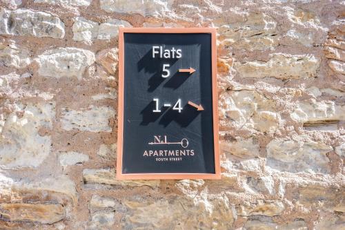 a clock on the side of a stone wall at No1 Apartments St Andrews - South Street in St. Andrews