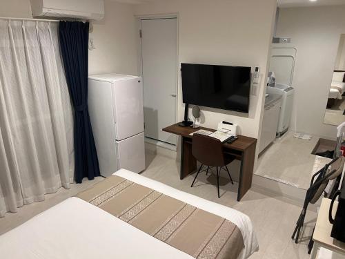 a bedroom with a desk with a television and a bed at Living Inn Nahakoumae in Naha