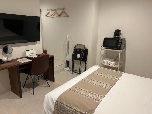 a bedroom with a bed and a desk and a television at Living Inn Nahakoumae in Naha