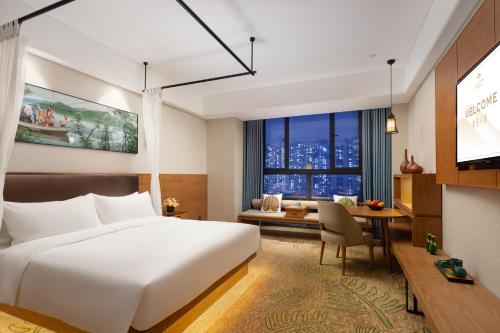 Una habitación de hotel con una cama, un escritorio y un televisor. en Relins Grand Madison Hotel, en Guangzhou