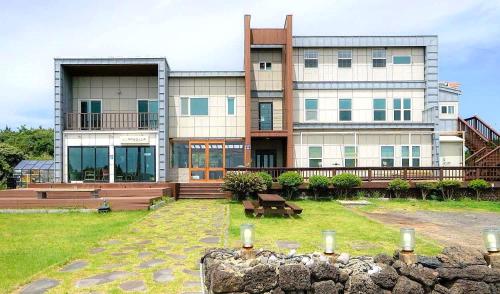 a large building with benches in front of it at Jeju Neulboyi Ohu Pensyeon in Jeju