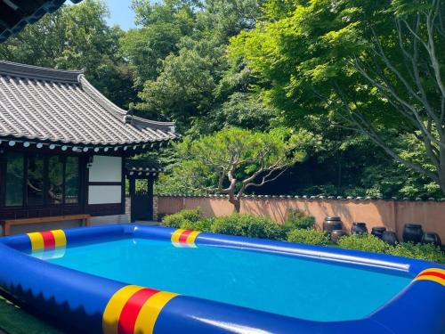 a swimming pool in a backyard with a building and trees at Paju Salimchae Pension in Paju