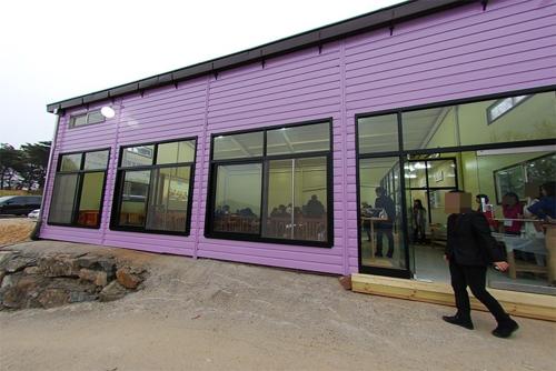a person walking past a purple building with windows at Paju Salimchae Pension in Paju