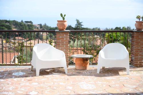 two white chairs and a table on a balcony at Etna Casa del Sole in Nicolosi