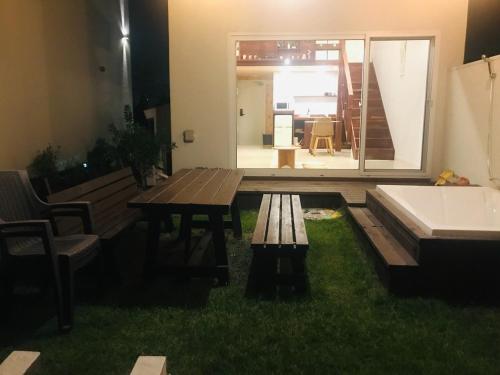 a patio with a table and a bench in the grass at Wasan Stay in Jeju in Jeju