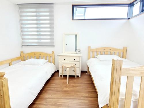 two twin beds in a room with a mirror at Jeju Hyeopjae Life in Jeju