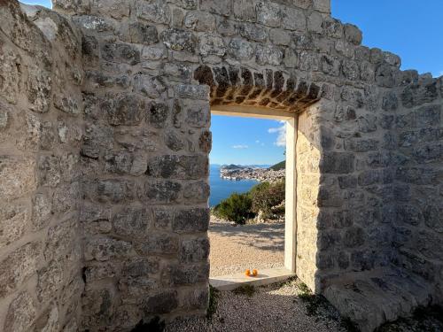an opening in a stone wall with a view of the ocean at Villa Anica Dubrovnik - luxurious with a sea view in Dubrovnik