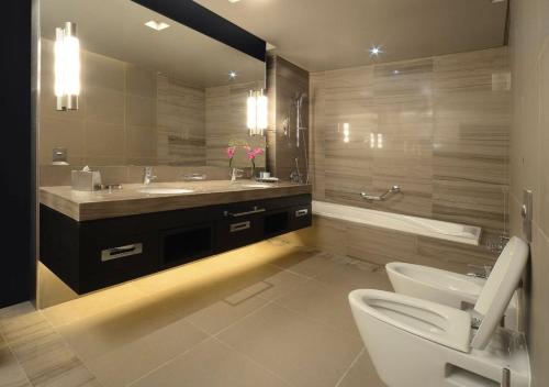 a bathroom with a sink and a toilet and a tub at The Abdali Boulevard Hotel in Amman