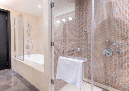 a bathroom with a shower and a sink and a glass shower stall at The Abdali Boulevard Hotel in Amman