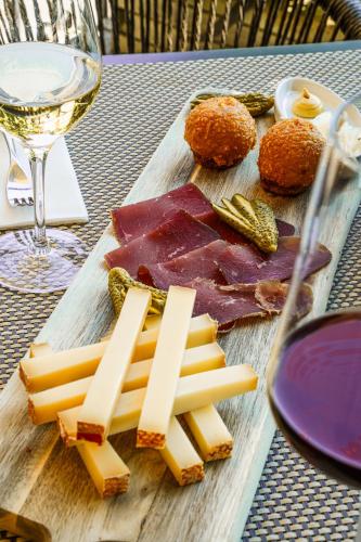 a wooden cutting board with cheese and a glass of wine at Rivage Hotel Restaurant Lutry in Lausanne