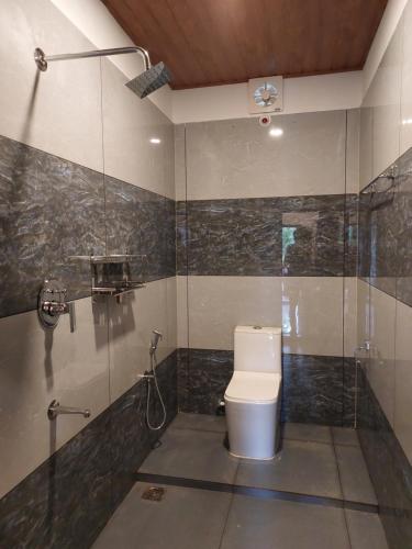 a bathroom with a toilet and a glass shower at Marari Beach Way Inn in Alleppey