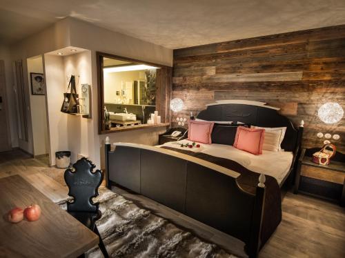a bedroom with a large bed and a mirror at Alpin Juwel - Bio und Lifestylehotel in Saalbach Hinterglemm