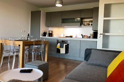 un salon et une cuisine avec un canapé et une table dans l'établissement Appartement neuf de standing Plage à pied, à Larmor-Plage