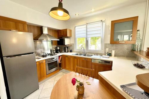 une cuisine avec des armoires en bois et un réfrigérateur en acier inoxydable dans l'établissement Maison de pêcheur - À 200m de la plage, à Ploemeur