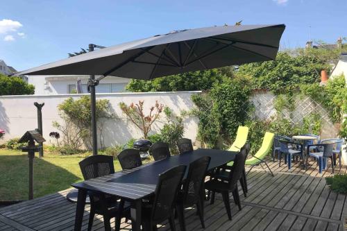une table noire avec des chaises et un parasol sur une terrasse dans l'établissement Maison de pêcheur - À 200m de la plage, à Ploemeur