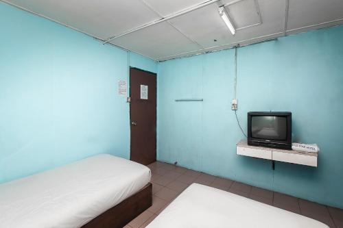 a small room with a bed and a tv at Hotel O Gold Star Hotel in Sibu