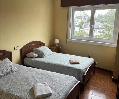 sypialnia z dwoma łóżkami i oknem w obiekcie Grupo Gontad Apartamento Cordobés, Ponteceso w mieście A Coruña