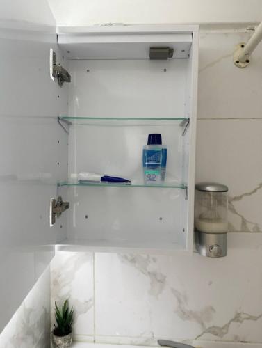 une armoire blanche avec des étagères en verre dans la cuisine dans l'établissement JungleRoom Connecté ! Au coeur du Vieux Nice, à Nice