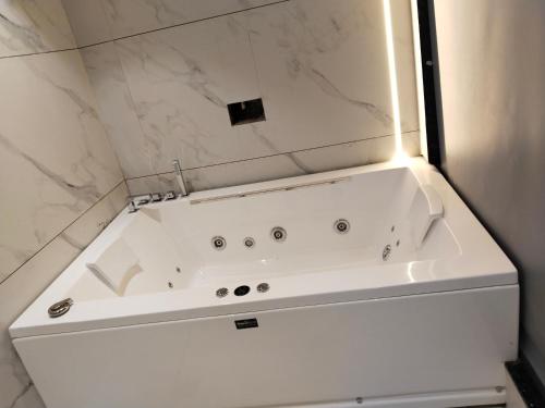 y baño con bañera blanca y paredes de mármol. en The Royal Velvet Hotel & Resort, en Rohtak