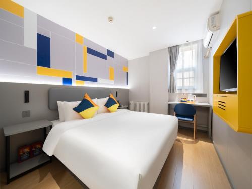 a bedroom with a large white bed and a tv at 7Days Inn Railway Station Xi'an Wulukou Subway Station in Xi'an